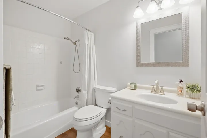 White paneled vanity with an integrated sink, brushed nickel faucet, and overhead three-bulb light fixture