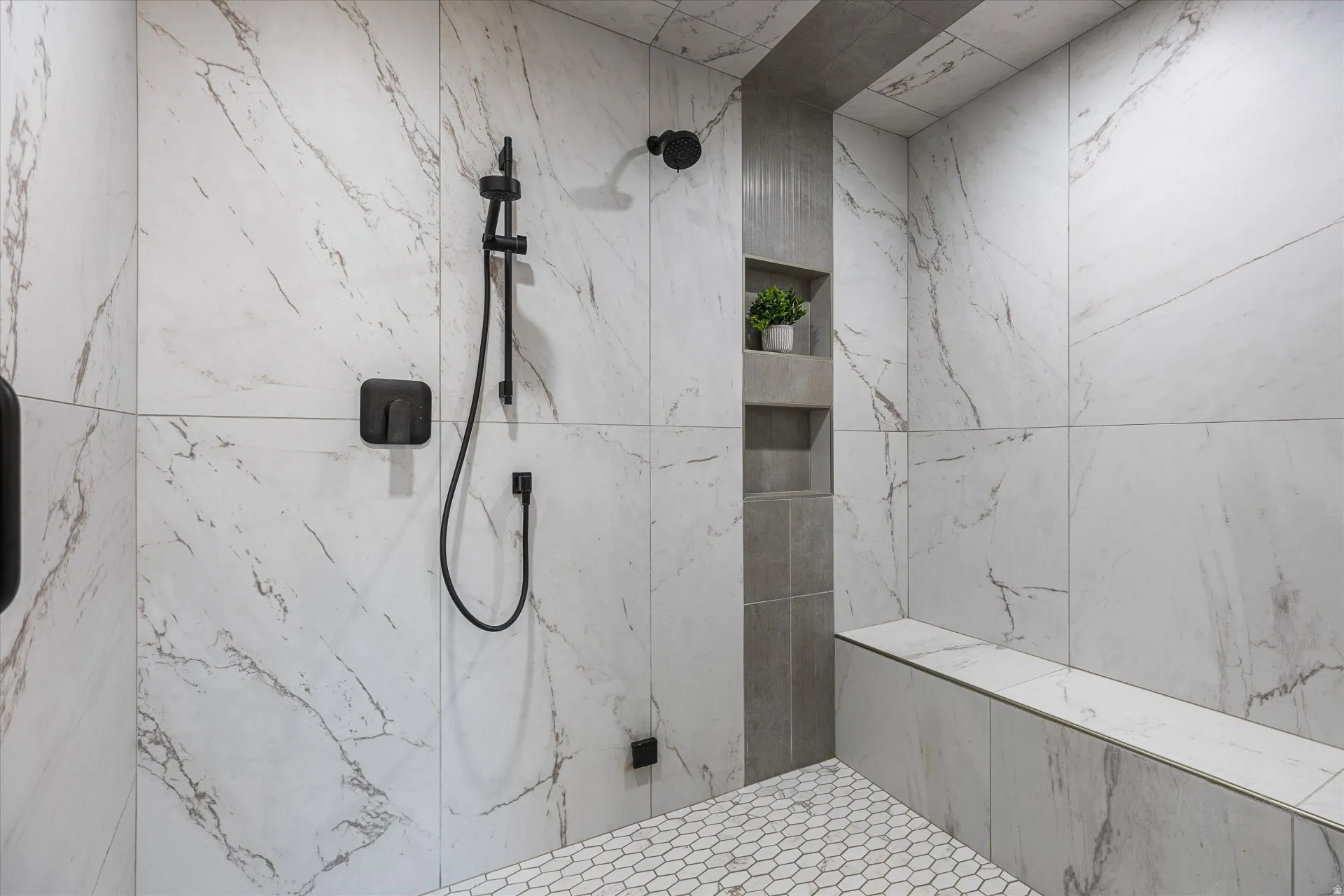 Primary shower detail — three shower heads, framed by a built-in bench.