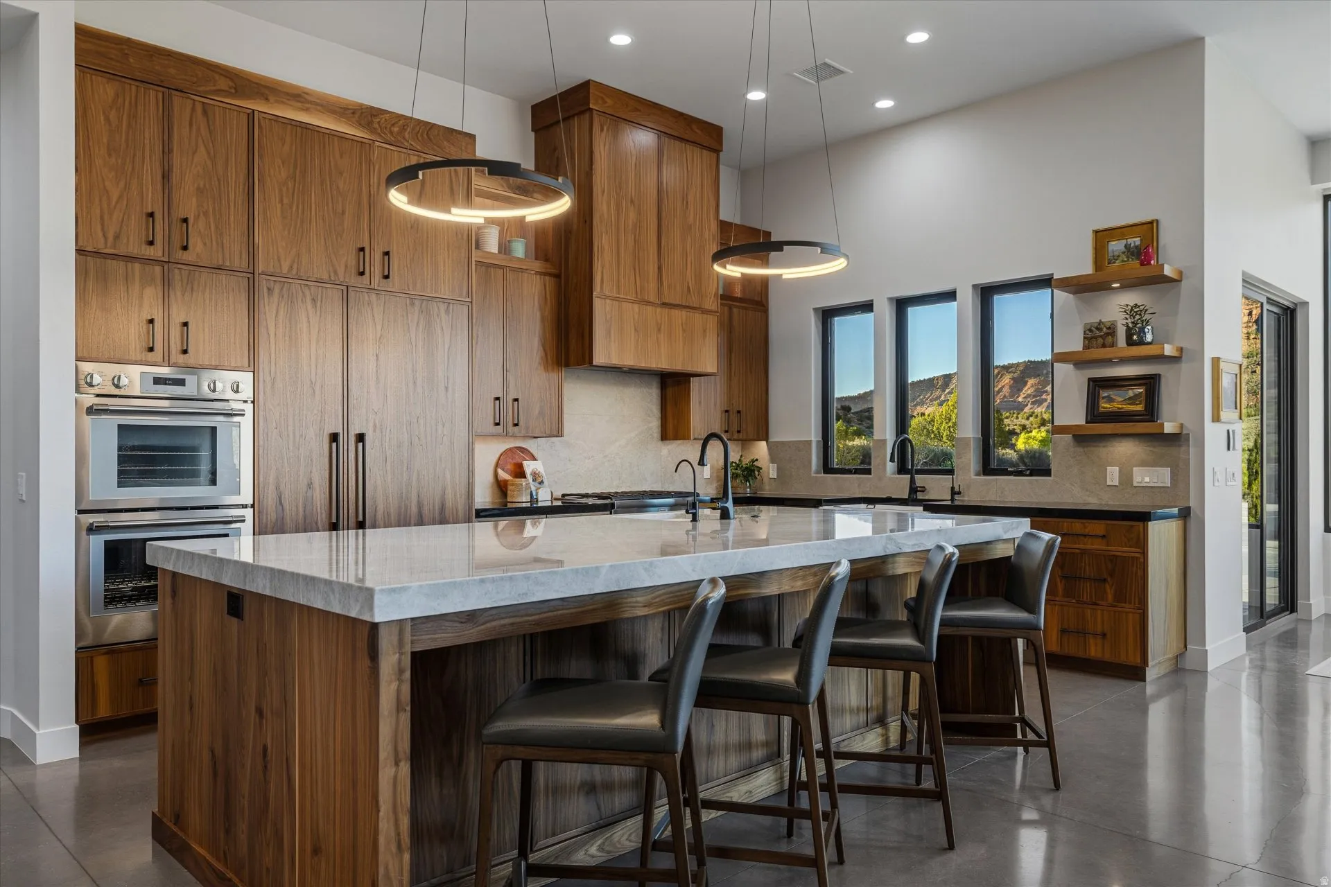 A Taj Mahal quartzite island anchors the kitchen, with ring pendant lighting overhead and a bar-height overhang for seating.