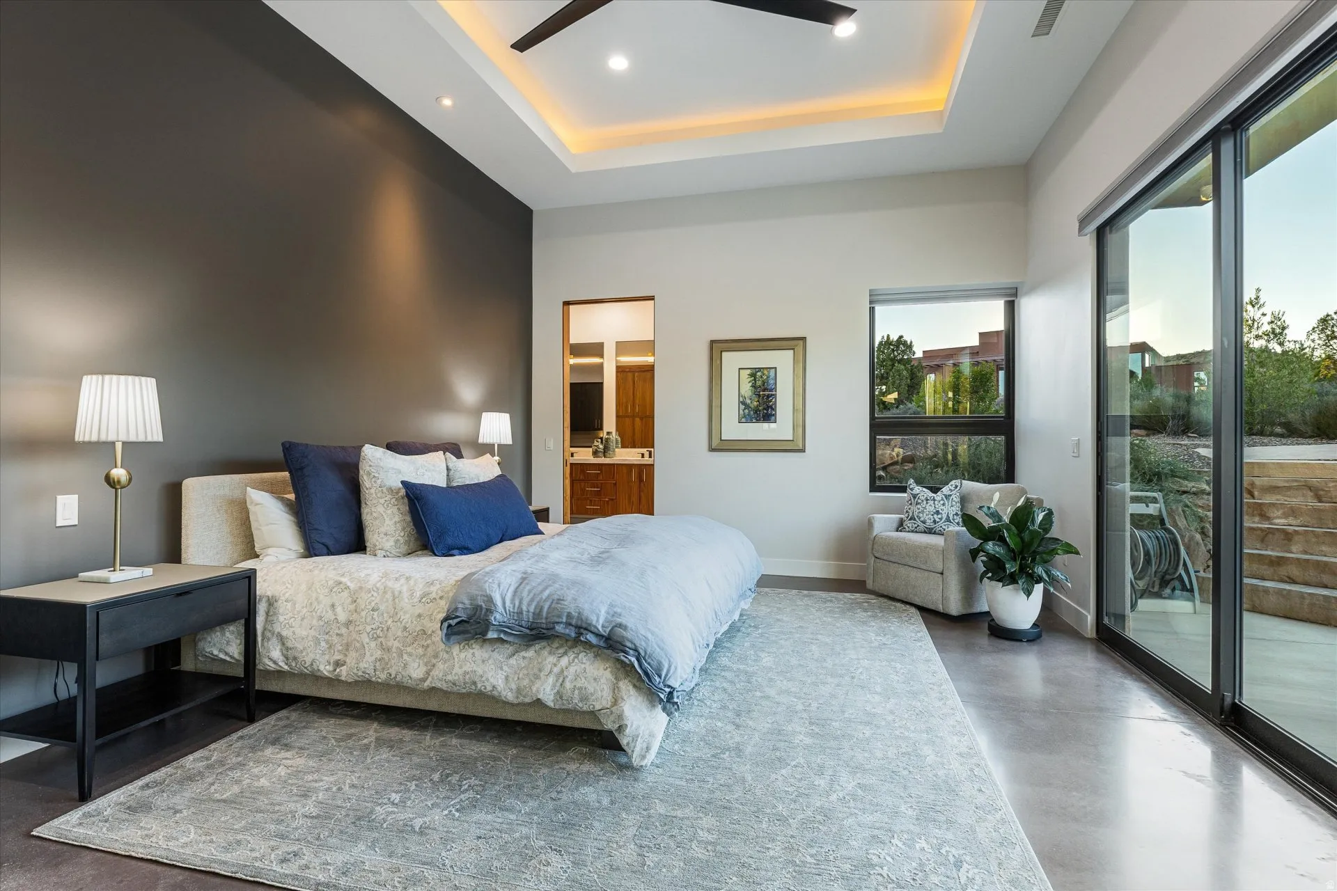 Primary suite opens to the pool patio through a slider, with a tray ceiling, fan, and direct access to a private outdoor space.