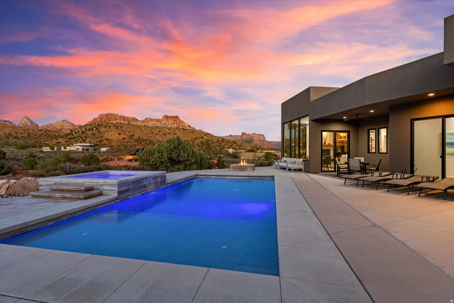 Pool patio with spa waterfall, a covered dining patio wired for outdoor sound (Martin Logan speakers, Sonos-integrated), and a fire pit.