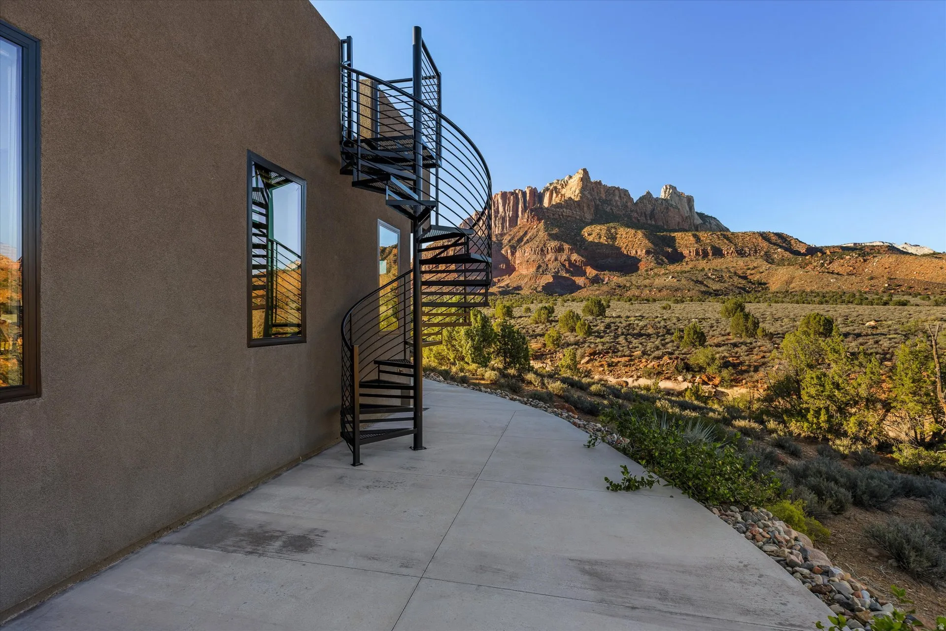 Wrought iron spiral staircase leading to the rooftop deck, Mt. Kinesava rising behind it.