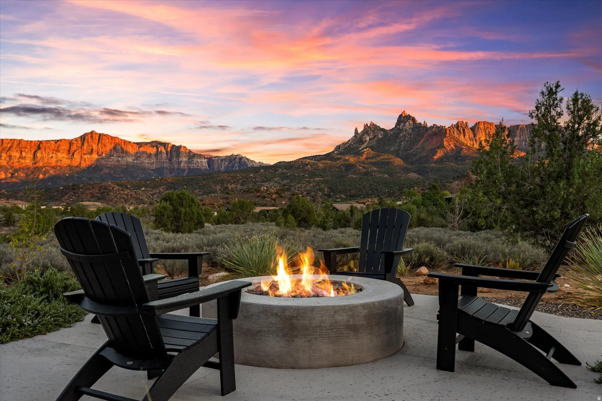 The front-yard fire pit glows as red rock silhouettes fade into the horizon.
