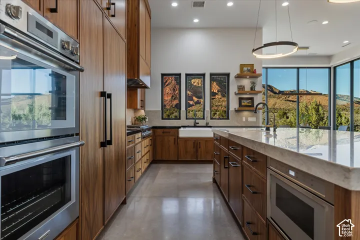 Thermador double wall ovens and a pro-style gas rangetop, set beneath a custom walnut hood, headline the kitchen.