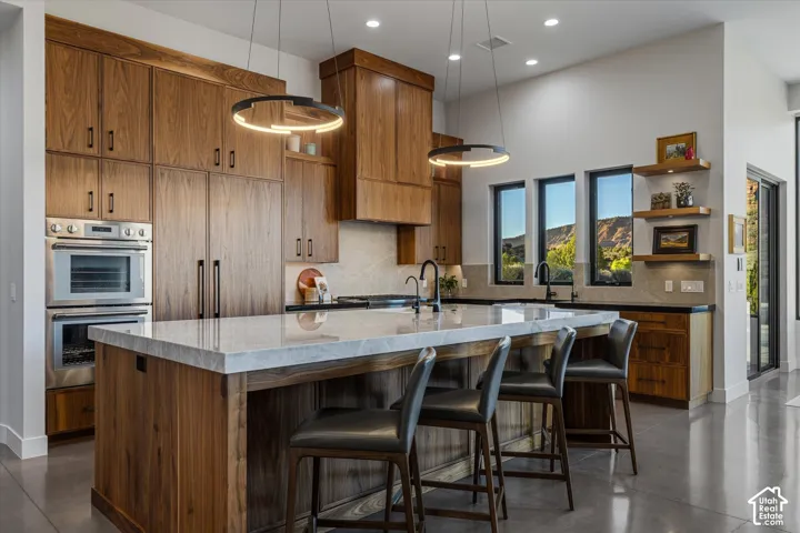 A Taj Mahal quartzite island anchors the kitchen, with ring pendant lighting overhead and a bar-height overhang for seating.