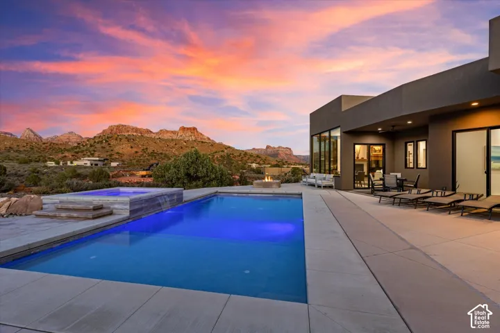 Pool patio with spa waterfall, a covered dining patio wired for outdoor sound (Martin Logan speakers, Sonos-integrated), and a fire pit.