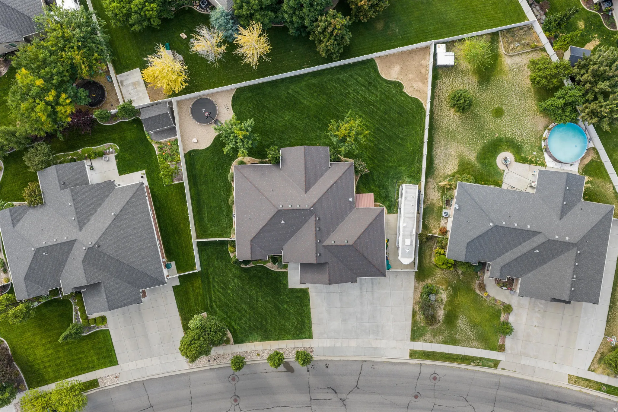Expansive property featuring a multi-gabled roofline, lush green lawns, mature trees, and a paved driveway