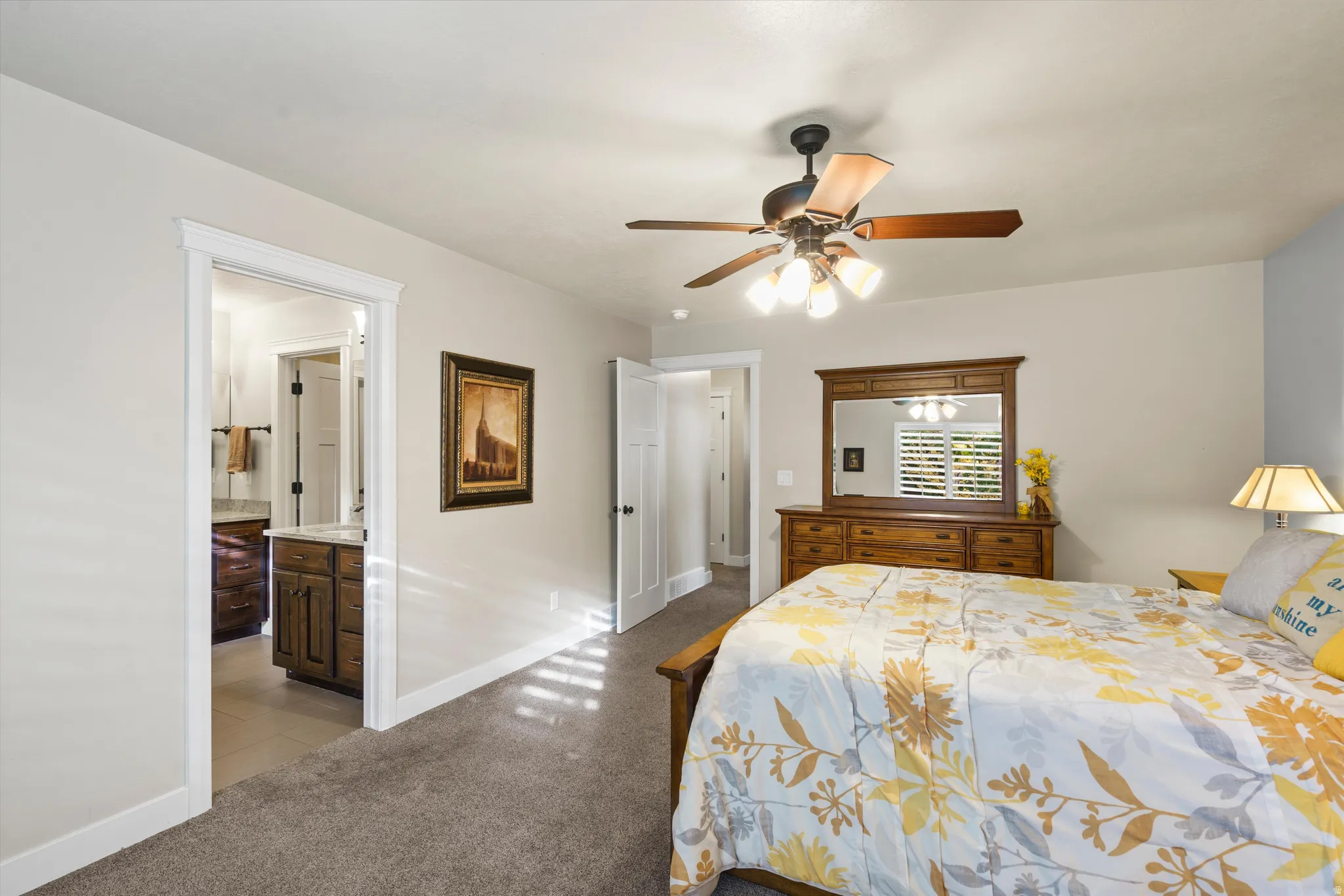 Ceiling fan with integrated lighting, soft gray wall paint, and plush carpet flooring