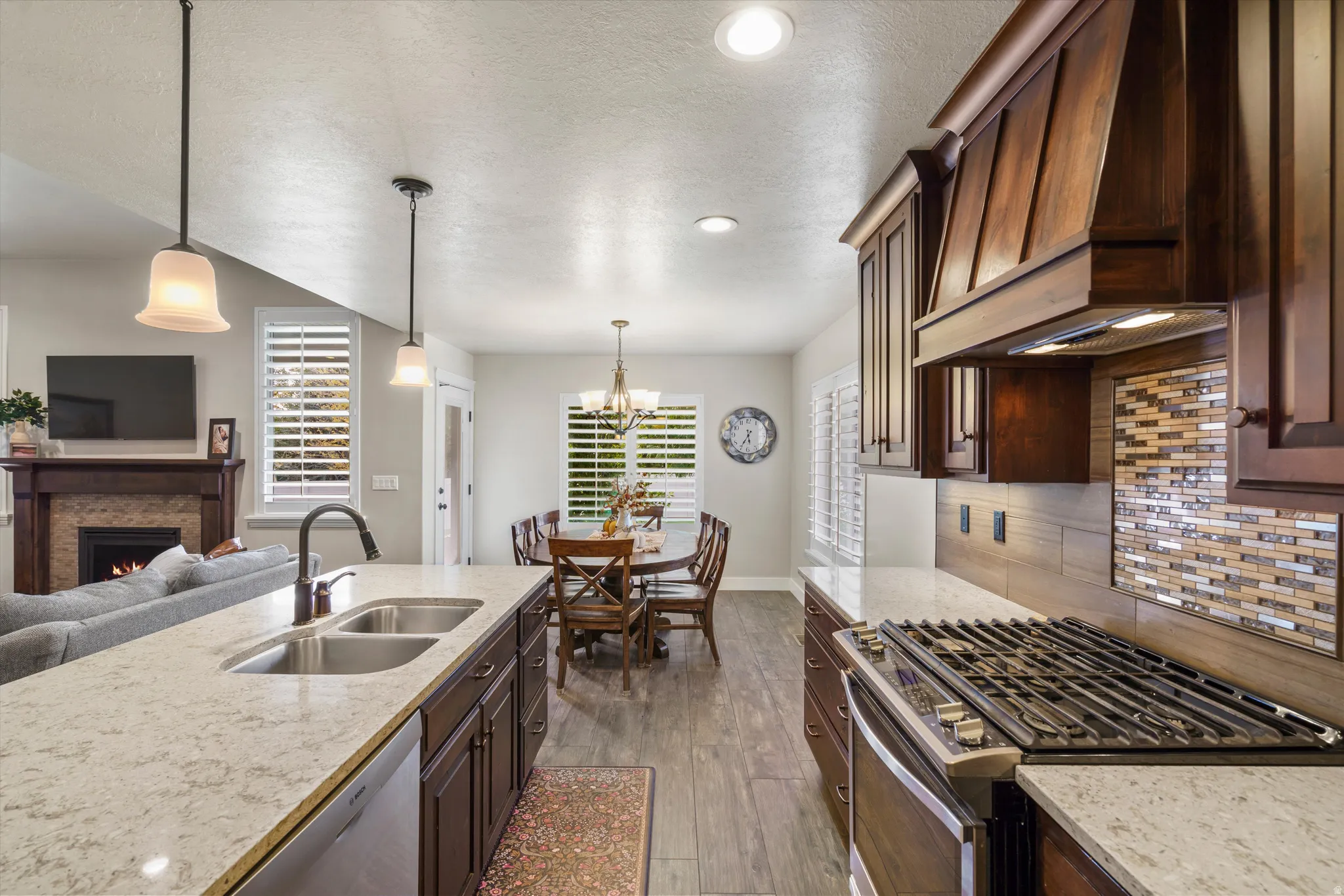 Gourmet kitchen with stainless steel gas range, mosaic tile backsplash, and wood-finish cabinetry