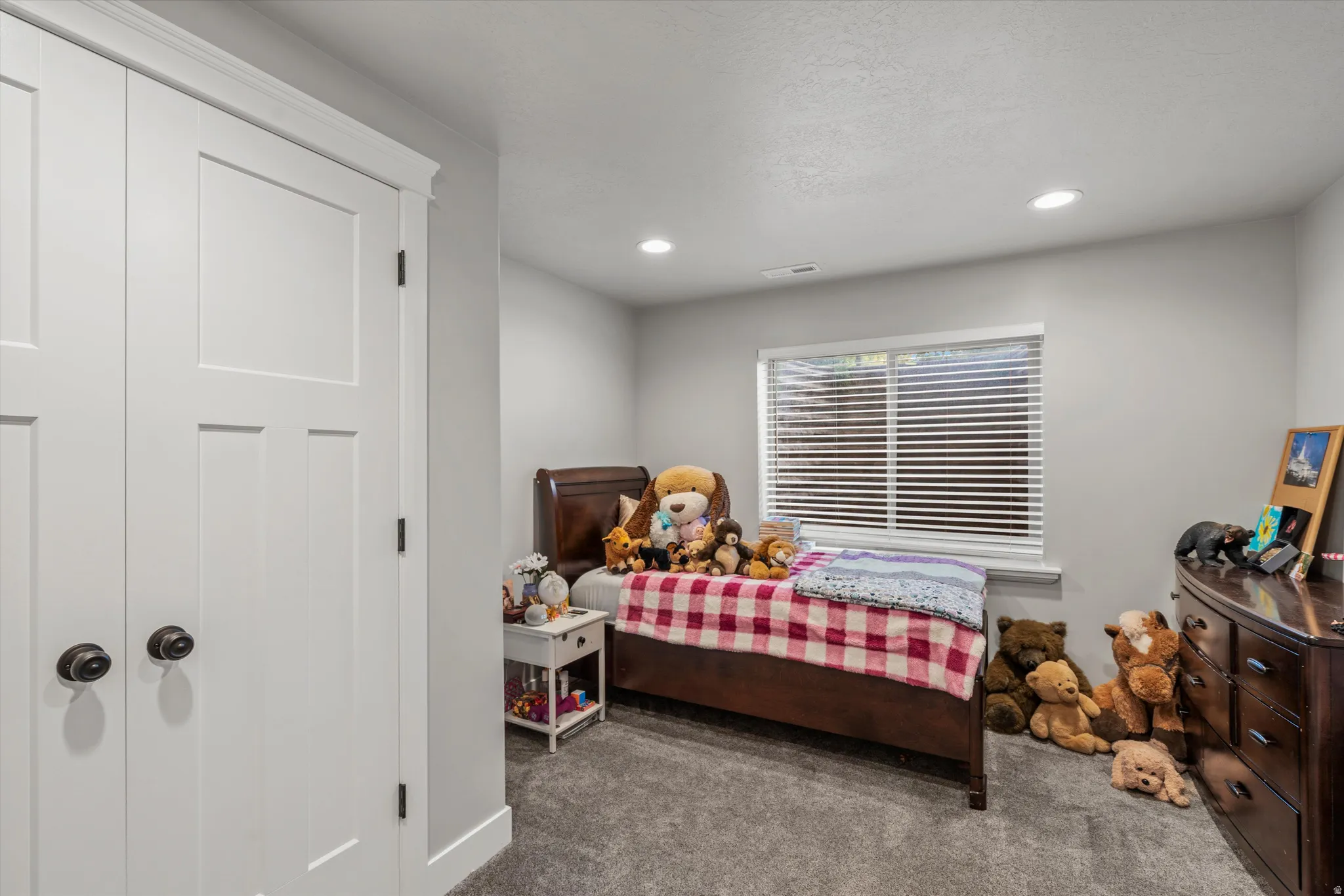Recessed lighting, light gray wall paint, window with horizontal blinds, gray carpet flooring, and white paneled closet doors