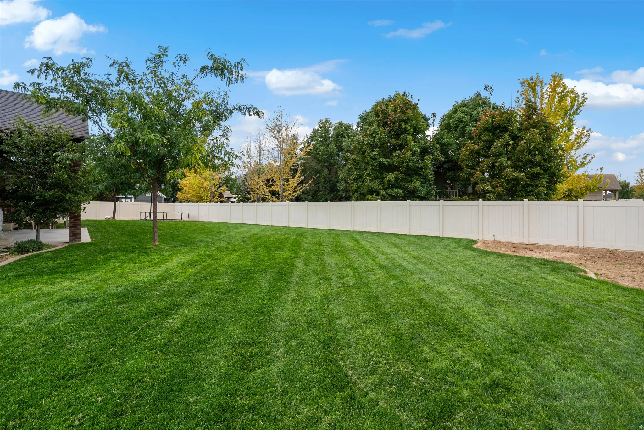 Expansive green lawn with a privacy fence and established trees