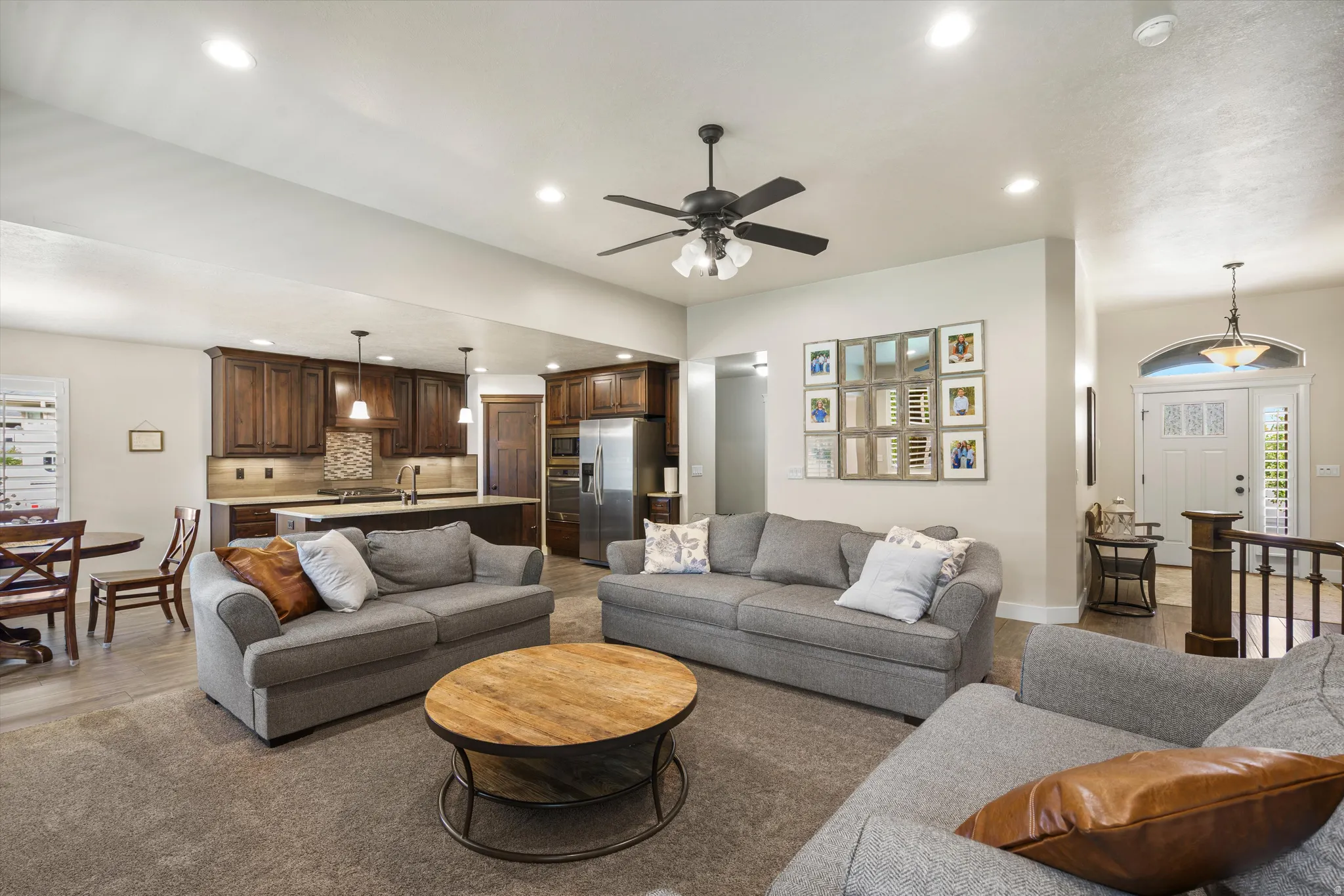 Open-concept living area with recessed lighting, ceiling fan, and wood-finish cabinetry