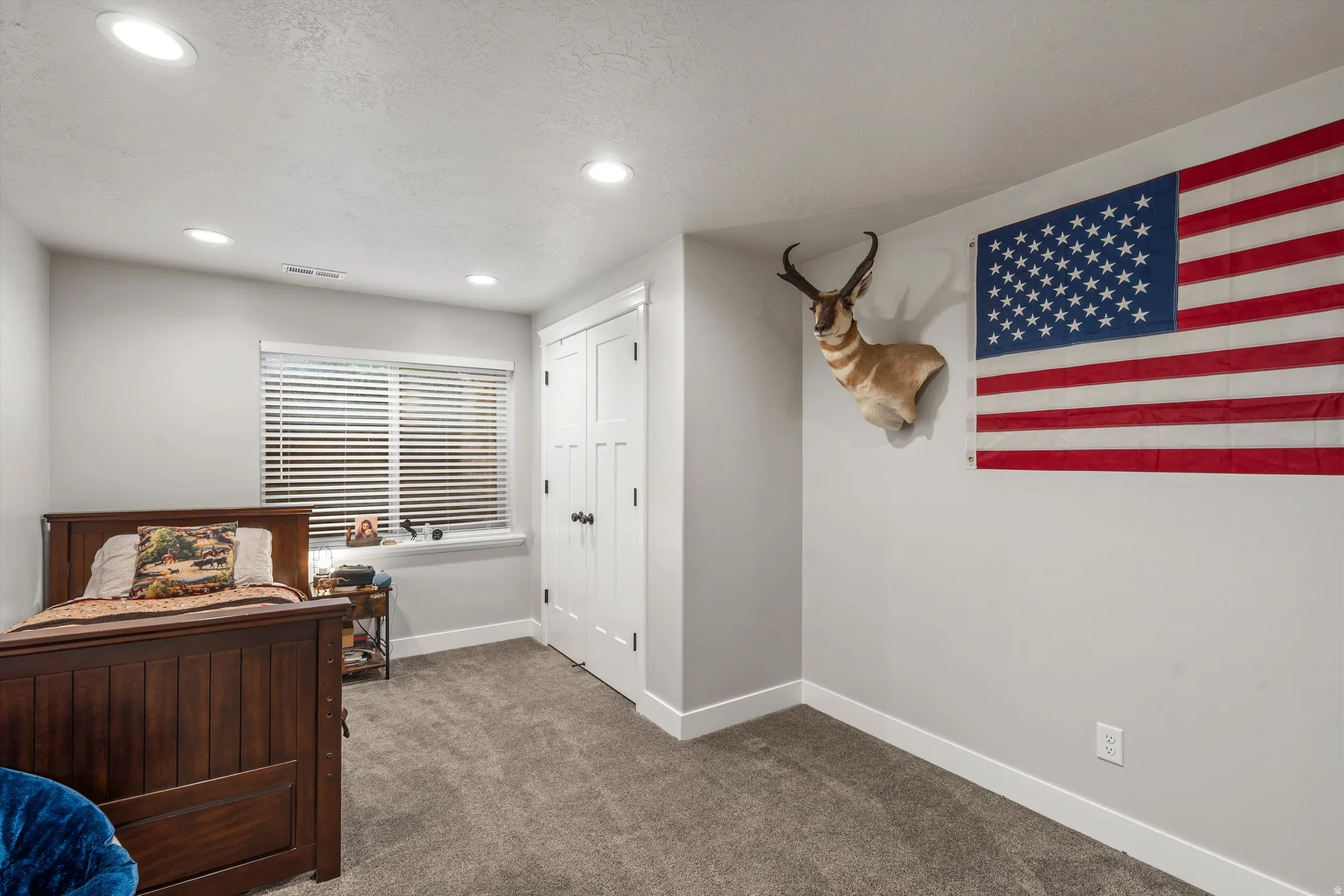 Recessed ceiling lighting, window with horizontal blinds, textured gray carpet, and white trim work