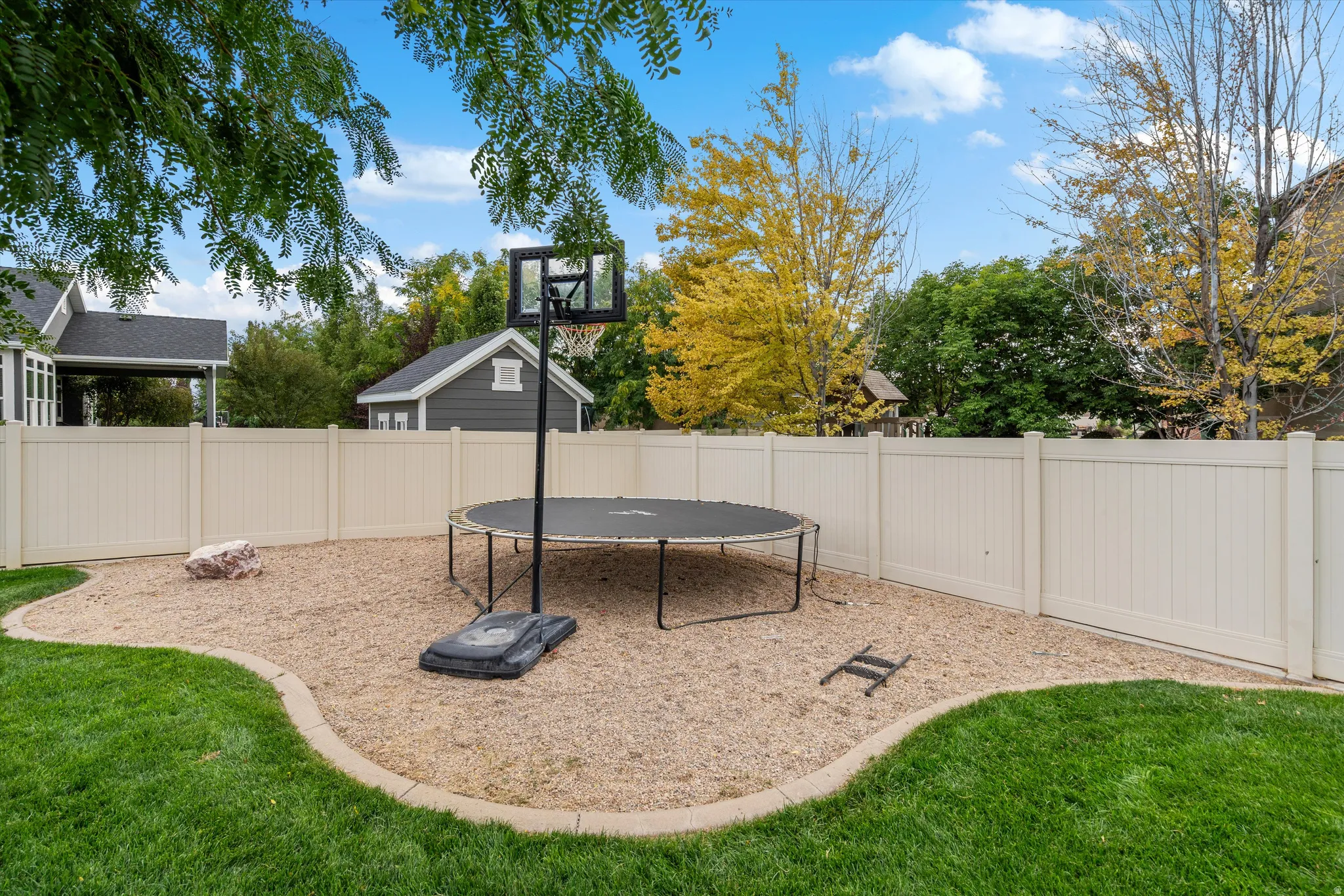 Landscaped backyard featuring a manicured lawn, defined gravel area, and full privacy fencing