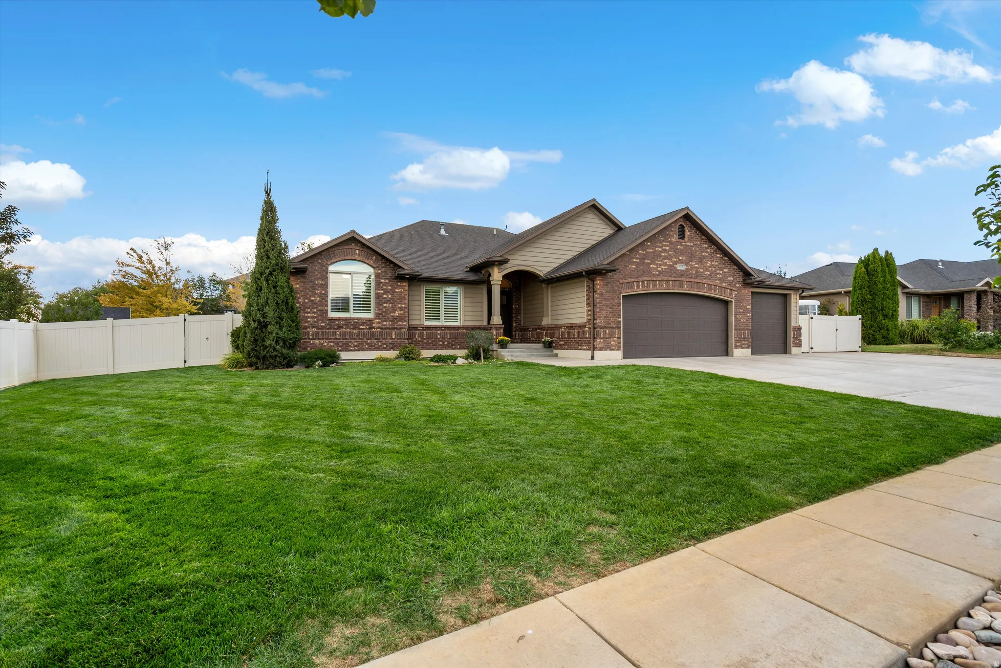 Brick and siding exterior with a dark roof, arched entry, two-car garage, and an additional single-car garage