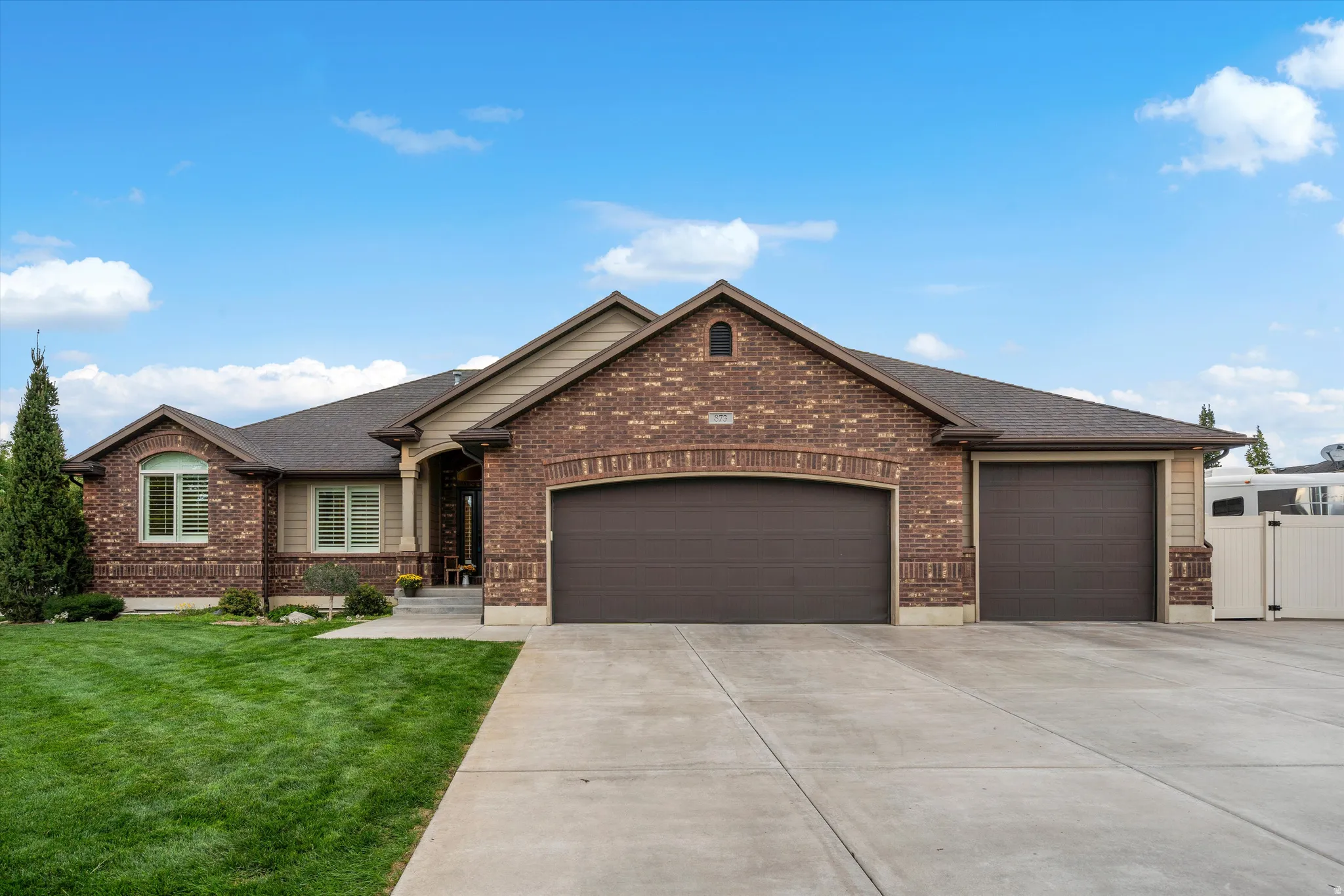 Brick and siding exterior with a multi-car garage, concrete driveway, and manicured lawn