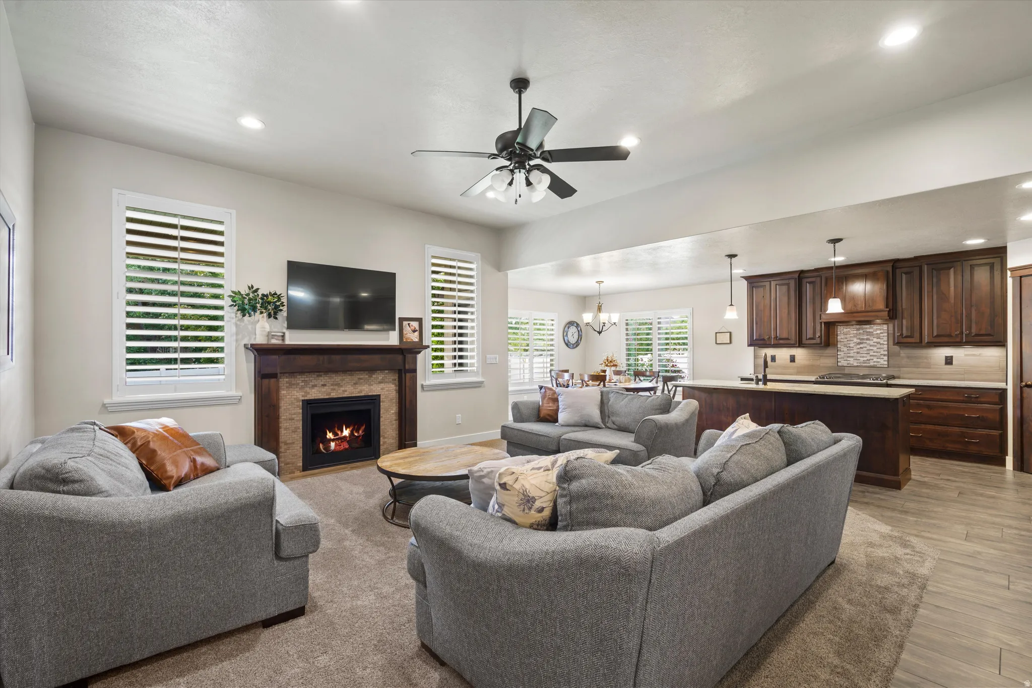 Living area featuring a fireplace with a wood-finish mantel and stone surround, recessed lighting, and a ceiling fan