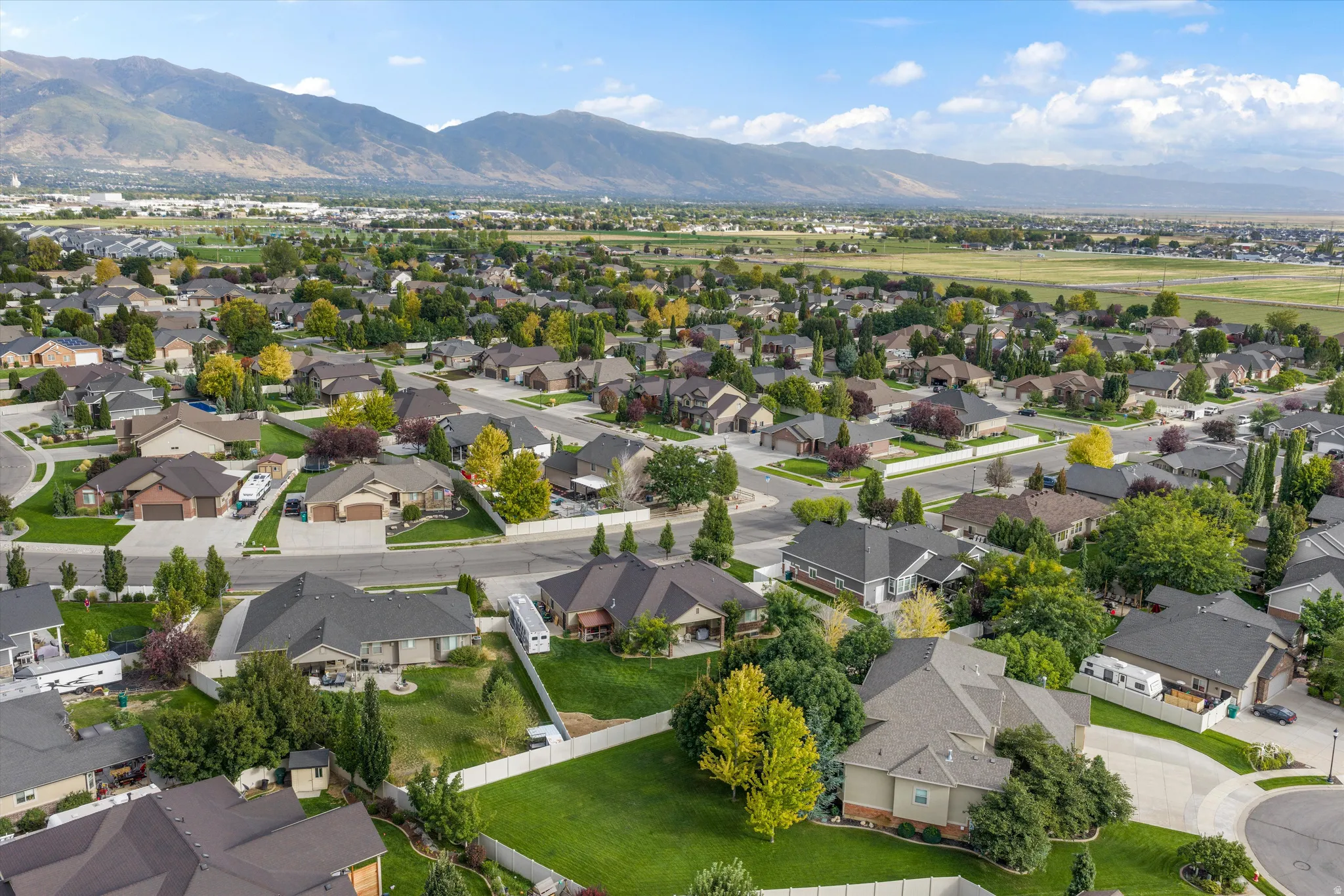 Residential neighborhood with mature trees, established landscaping, mountain backdrop, and paved streets