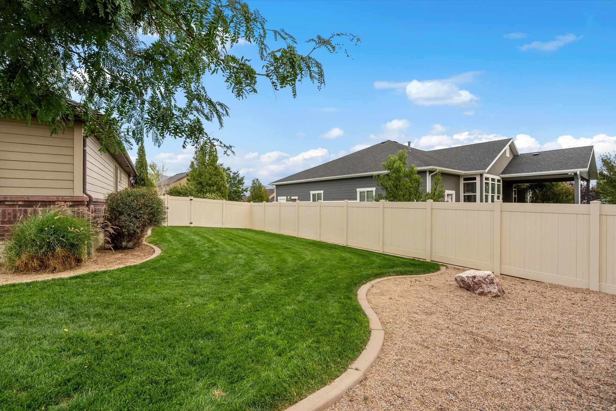 Manicured lawn with defined landscape curbing, surrounded by a light-toned privacy fence