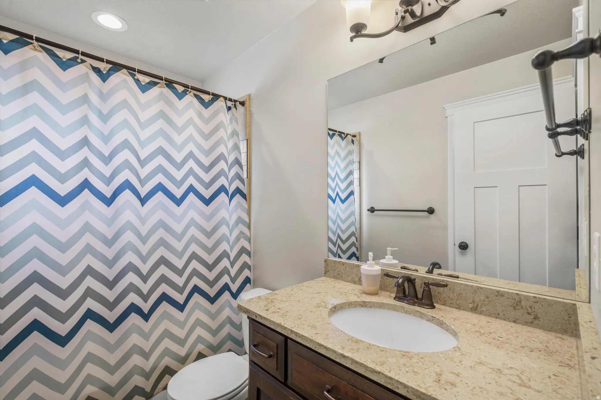 Bathroom featuring a single vanity with a light-toned countertop, an undermount sink, and a dark-finished faucet