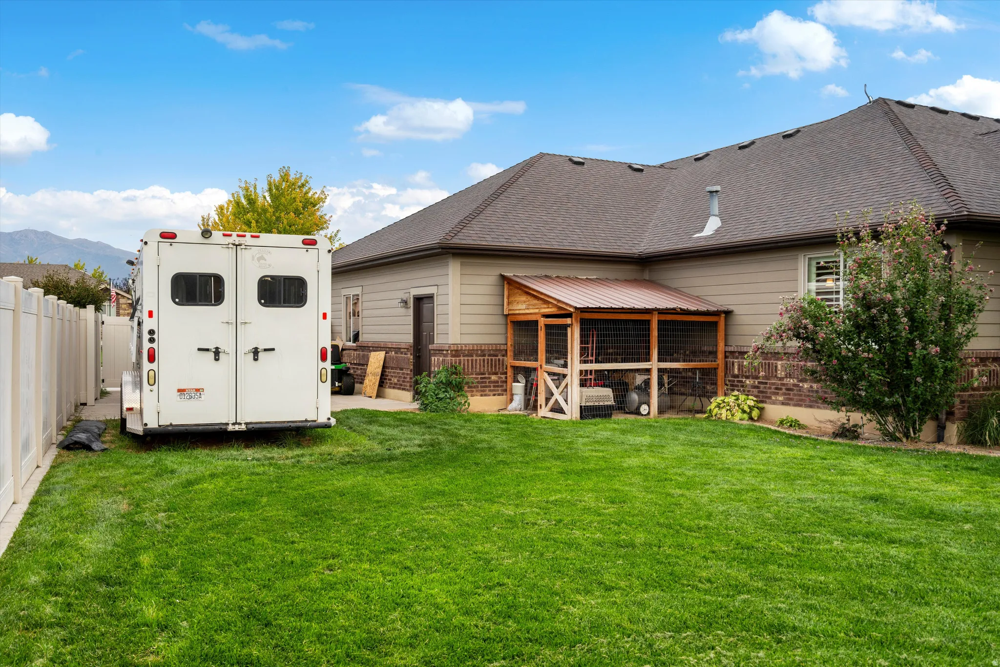 Spacious backyard with a vibrant green lawn, light-colored privacy fencing, and a detached structure featuring a metal roof