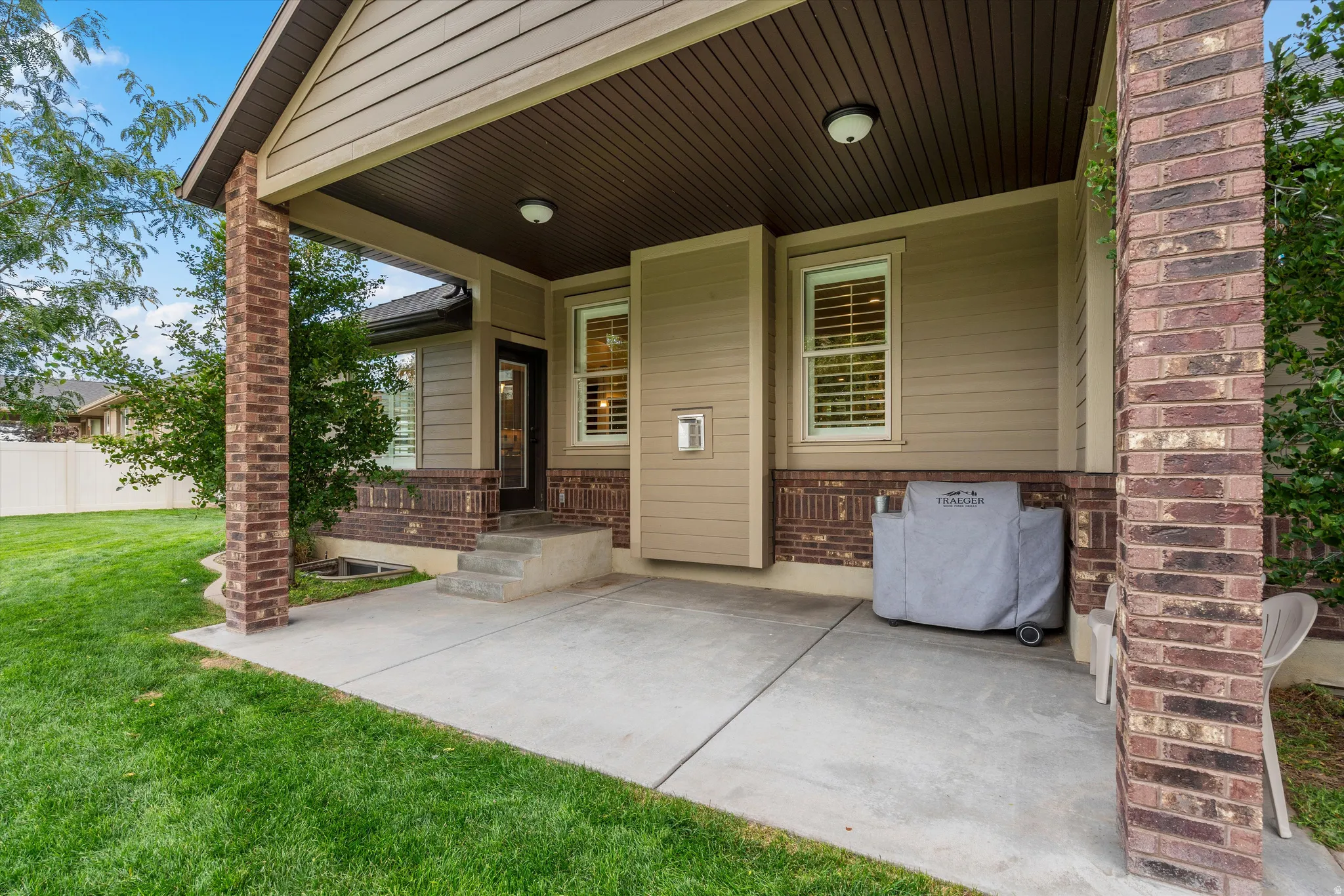 Covered patio with a concrete slab, brick columns, and a beadboard ceiling