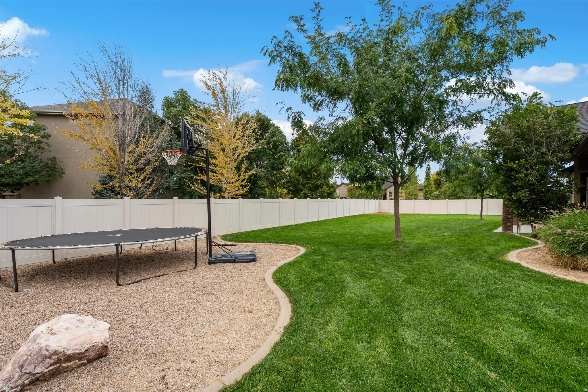 Expansive backyard featuring a manicured lawn, established trees, and a durable privacy fence