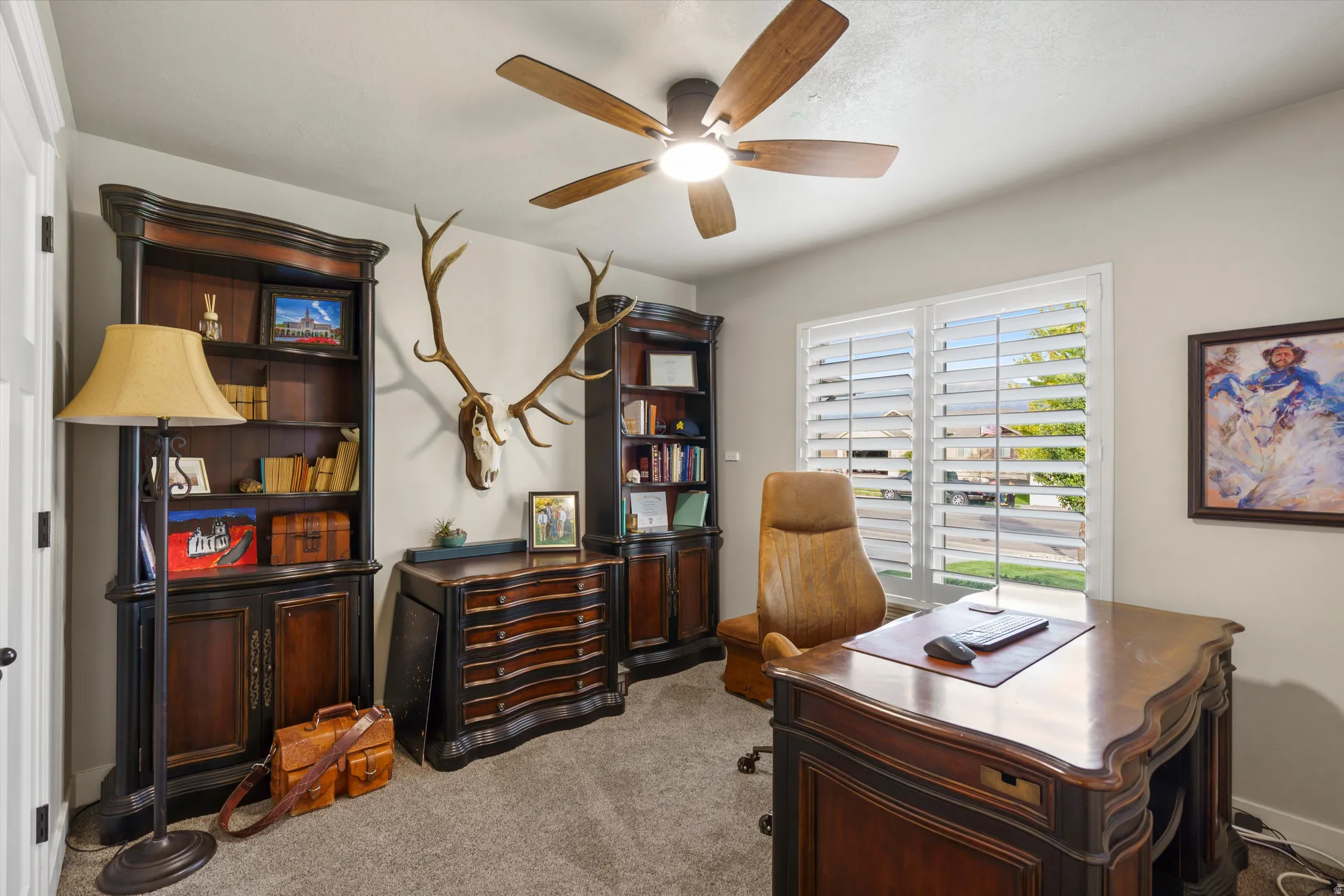 Plush carpet flooring, a ceiling fan with integrated lighting, and plantation shutters