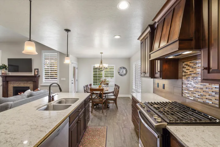 Gourmet kitchen with stainless steel gas range, mosaic tile backsplash, and wood-finish cabinetry
