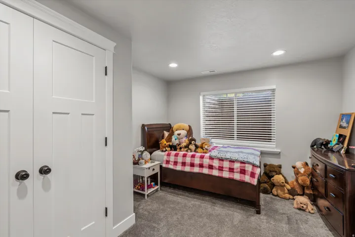 Recessed lighting, light gray wall paint, window with horizontal blinds, gray carpet flooring, and white paneled closet doors