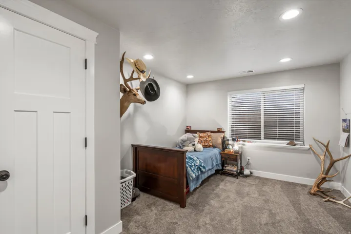 Recessed ceiling lighting, a white paneled door with dark hardware, a window with blinds, and neutral-toned wall paint