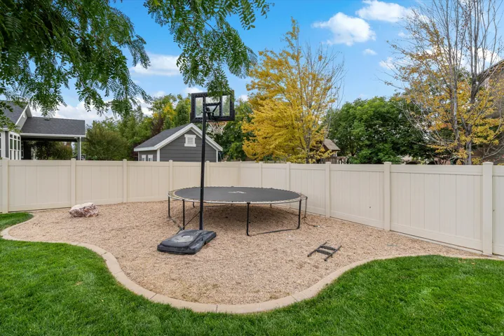 Landscaped backyard featuring a manicured lawn, defined gravel area, and full privacy fencing