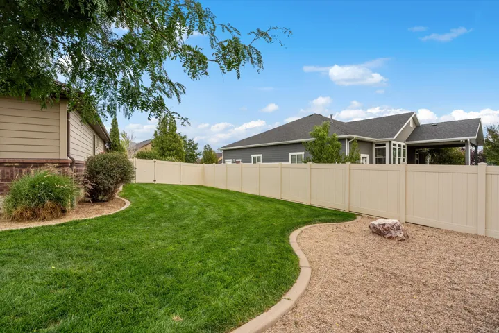 Manicured lawn with defined landscape curbing, surrounded by a light-toned privacy fence