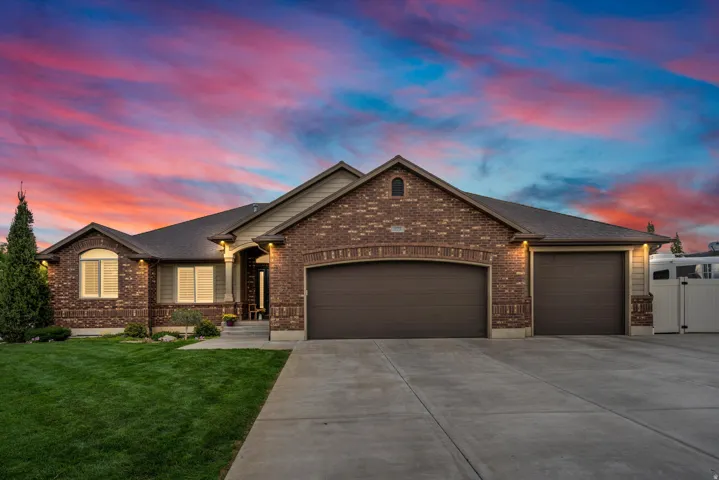 Brick exterior with accent siding, arched garage door, two additional garage doors, concrete driveway, and established front landscaping