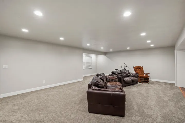 Recessed lighting illuminates a carpeted open-concept space with light gray walls