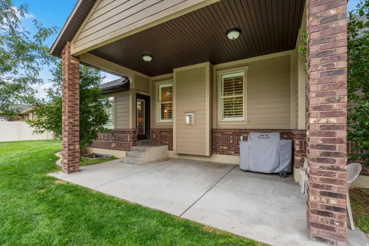 Covered patio with a concrete slab, brick columns, and a beadboard ceiling