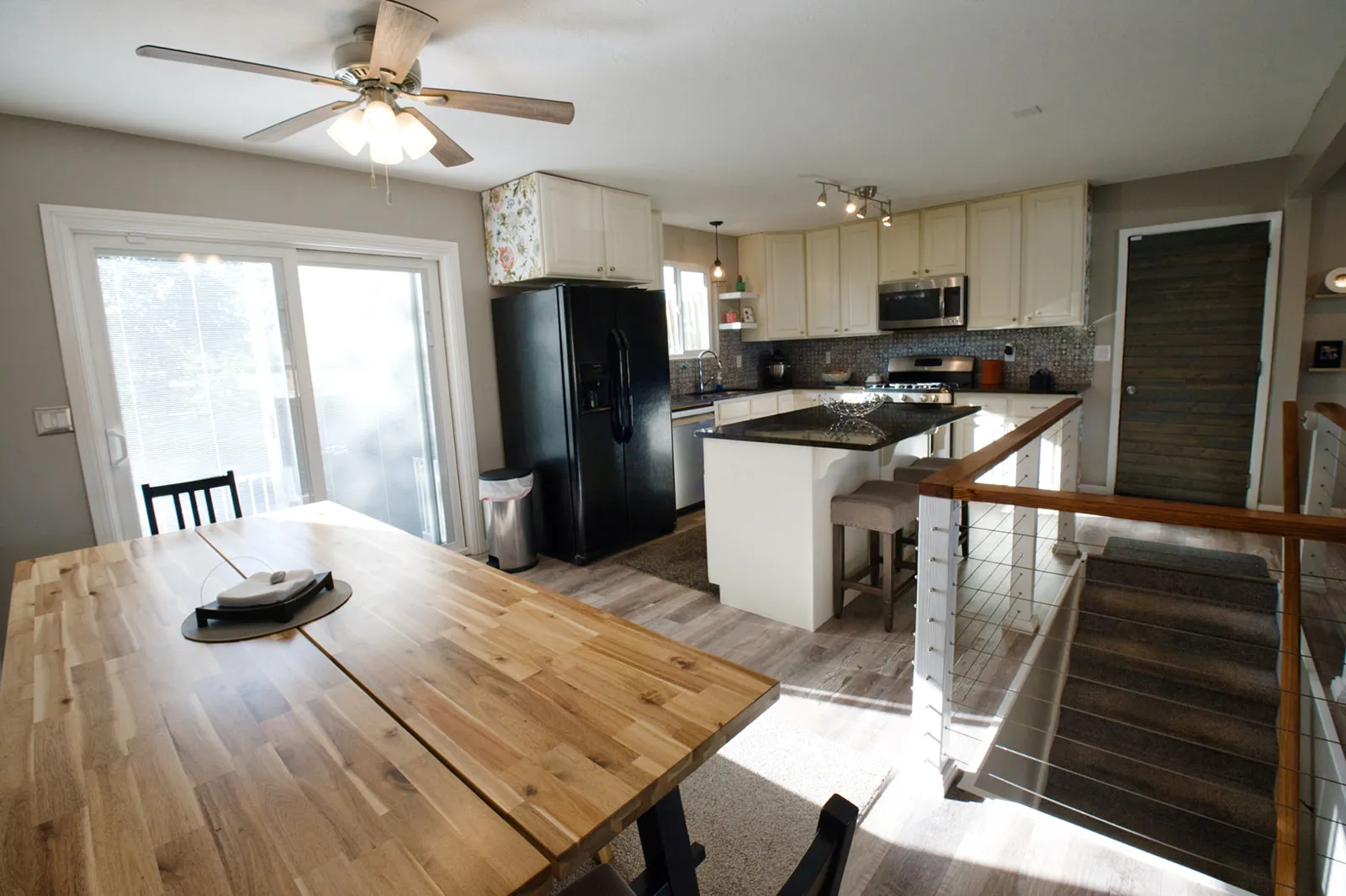 Kitchen featuring stainless steel appliances, dark stone countertops, tile backsplash, and light-toned cabinetry