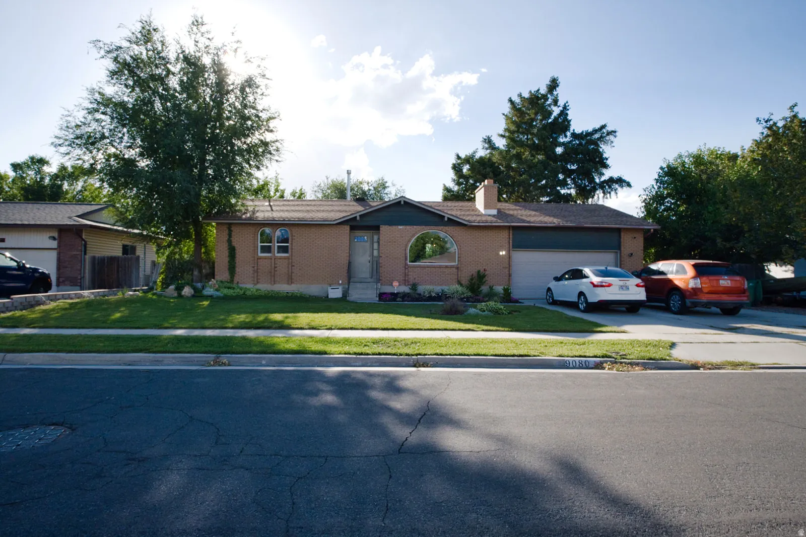 Brick exterior with an arched window, attached garage, and a concrete driveway