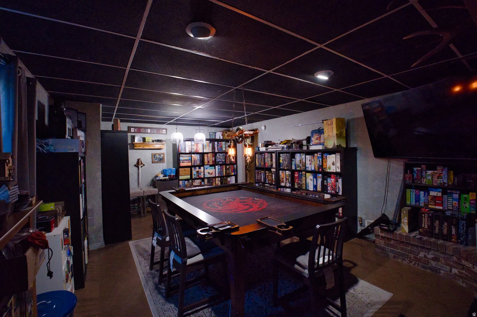 Finished room featuring a dark grid ceiling, recessed lighting, and a brick-finish hearth