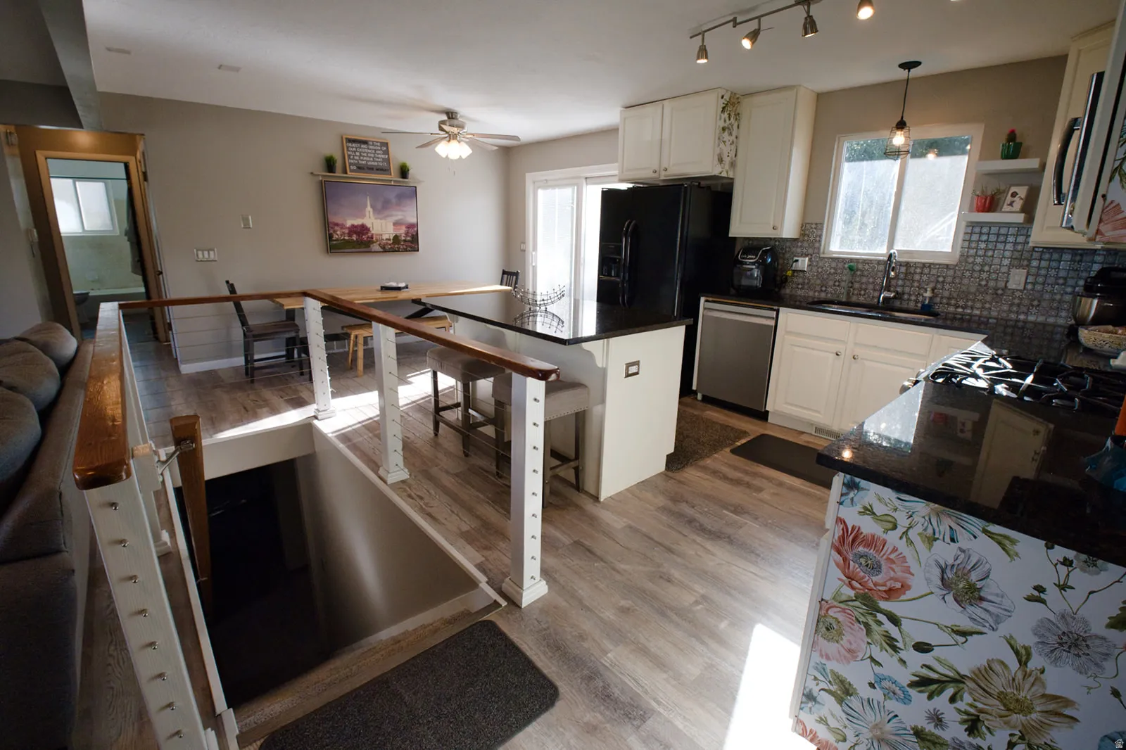 Open-concept kitchen and dining area featuring wood-finish flooring, white cabinetry, dark countertops, and stainless steel appliances