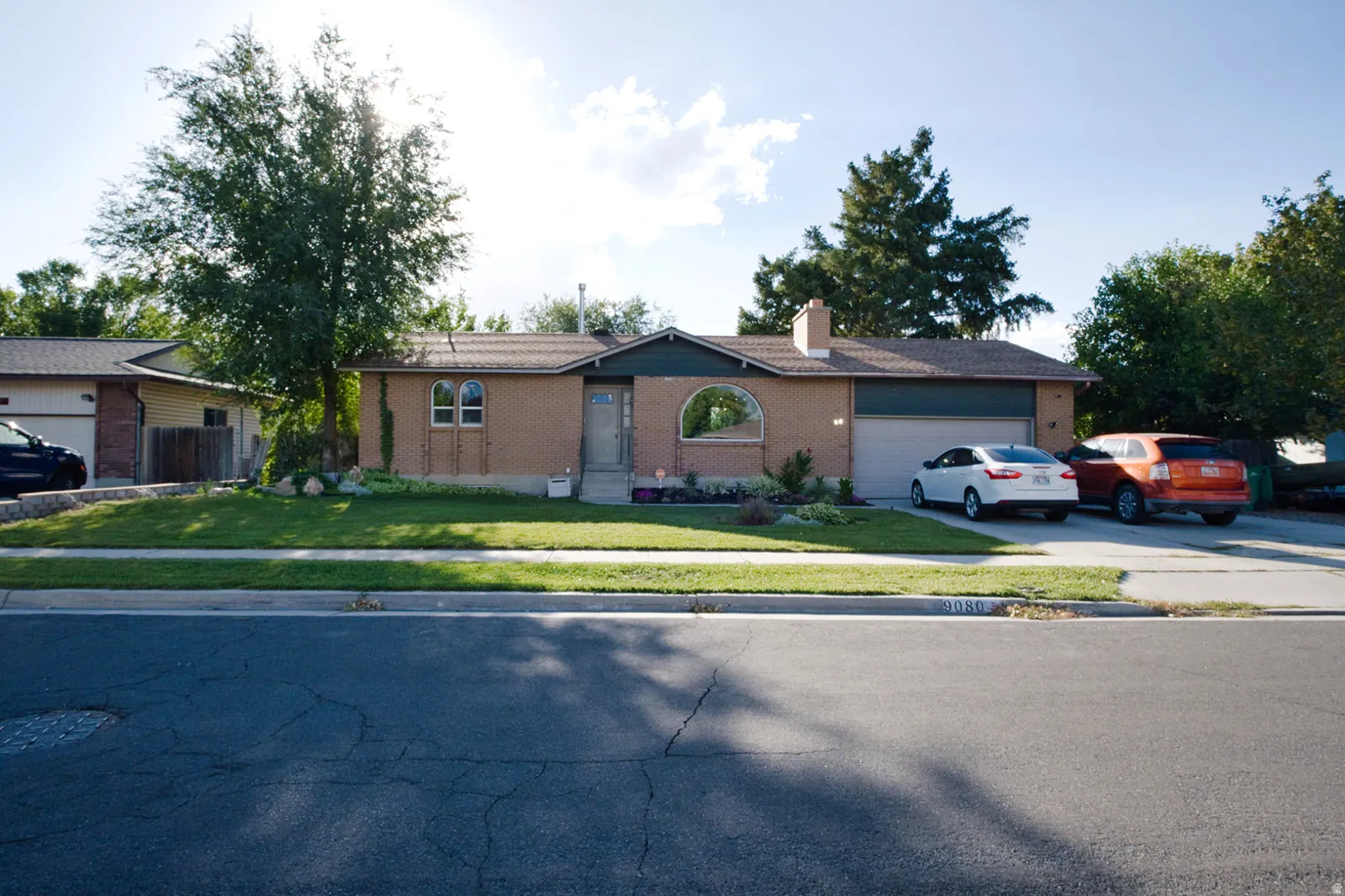 Brick exterior with arched windows, attached garage, and established landscaping