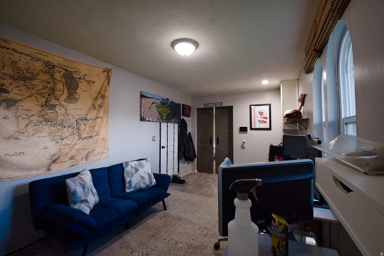 Arched windows with window treatments, recessed lighting, flush-mount ceiling light, and permanent built-in shelving