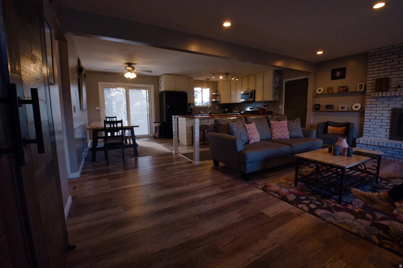 Wood-finish flooring throughout, with a white-painted brick fireplace and mantel