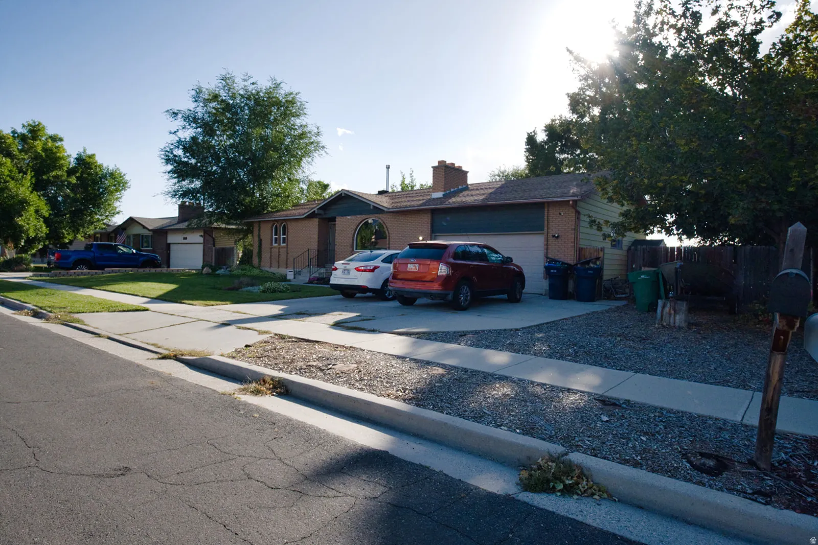 Brick facade with a prominent round window, attached garage, and a gravel driveway