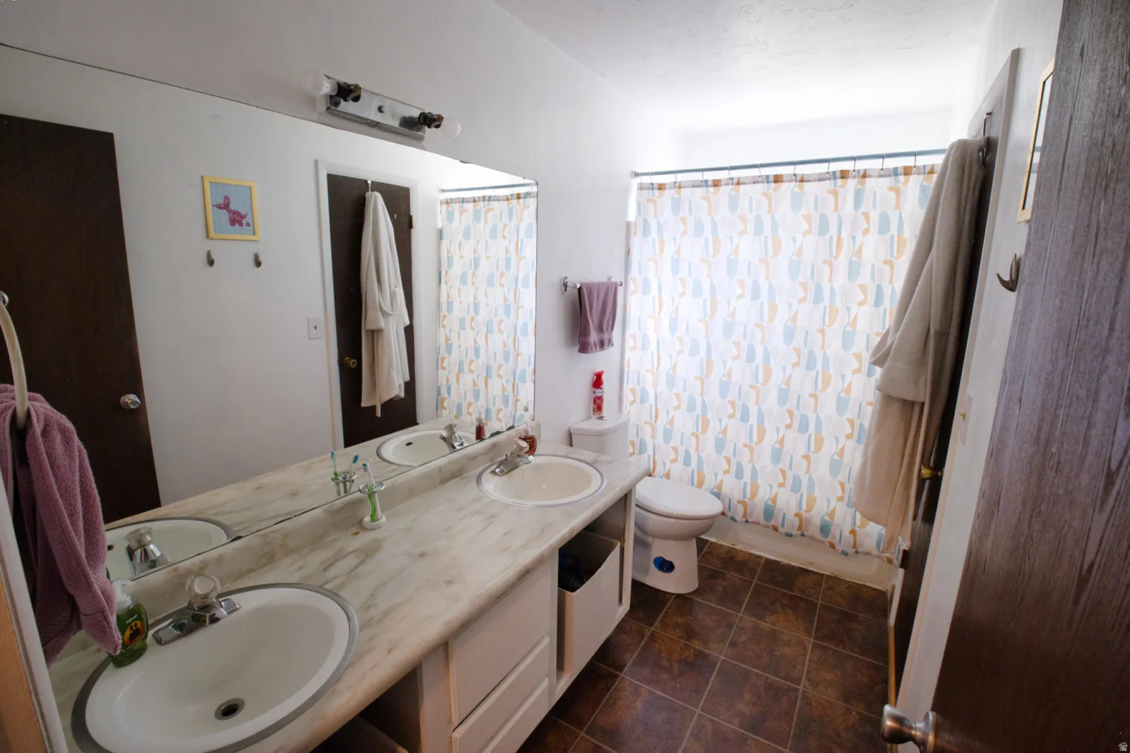Dual vanity with integral sinks, large wall-mounted mirror, and tile flooring