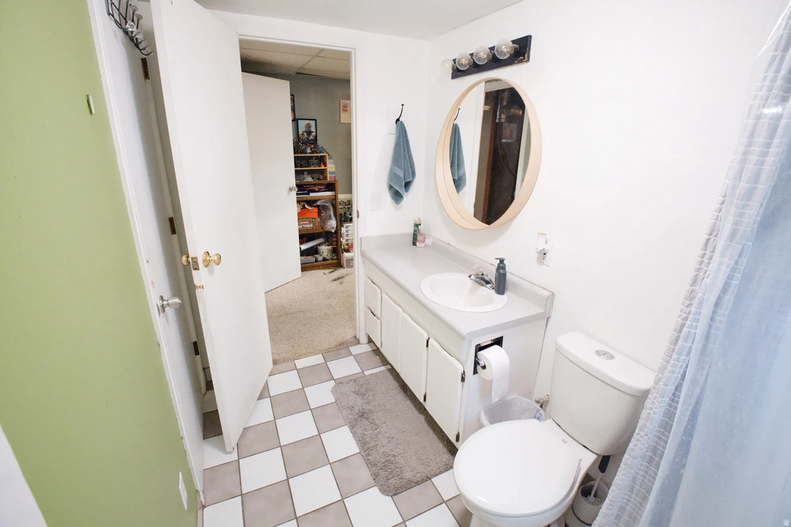 White vanity with an integrated sink, a rounded mirror, and a three-light fixture
