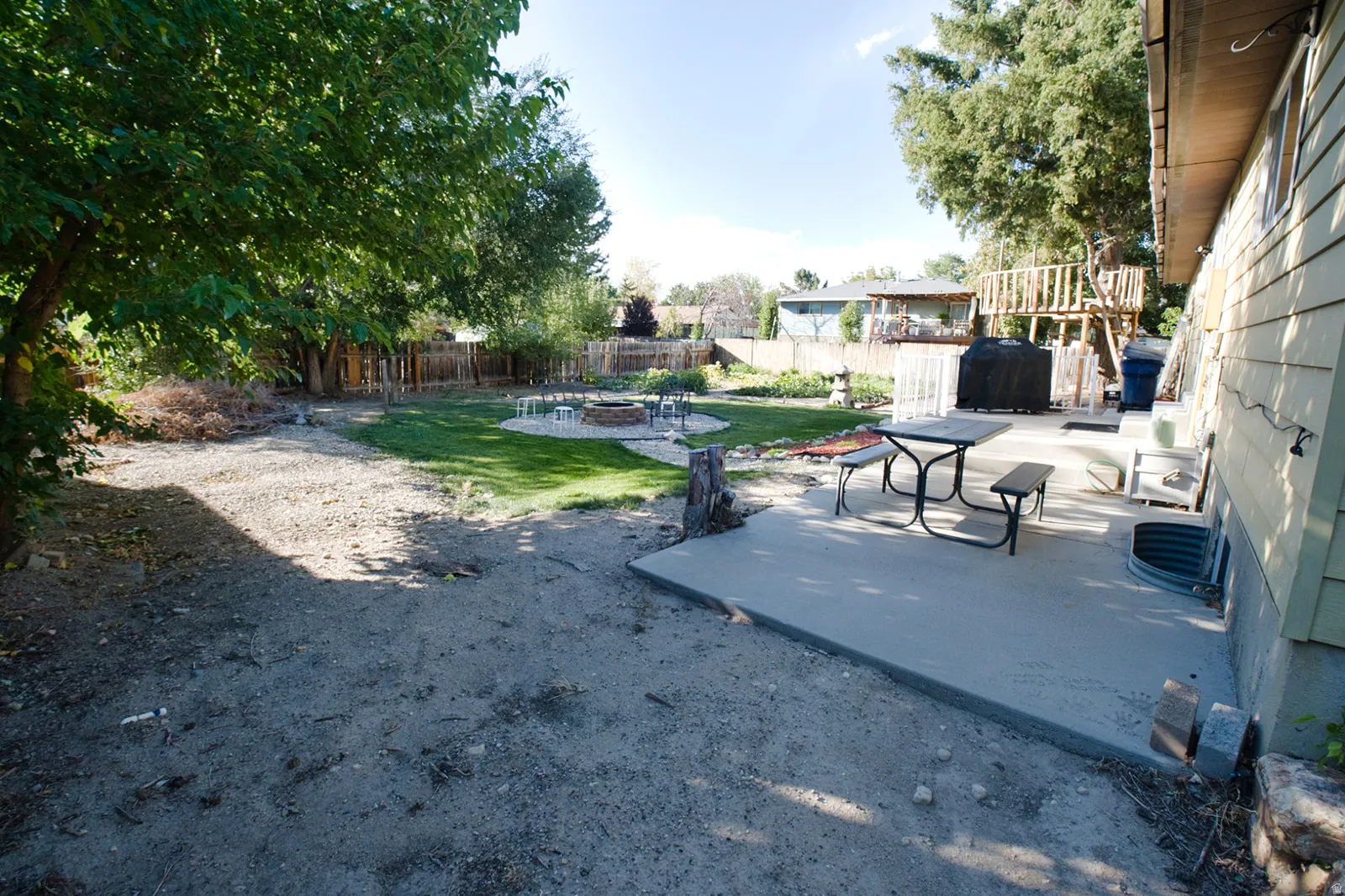 Expansive backyard featuring a concrete patio, a manicured lawn, and mature trees
