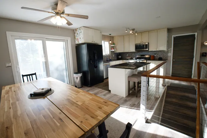 Kitchen featuring stainless steel appliances, dark stone countertops, tile backsplash, and light-toned cabinetry