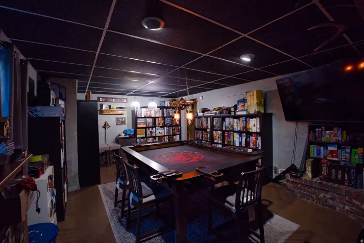 Finished room featuring a dark grid ceiling, recessed lighting, and a brick-finish hearth
