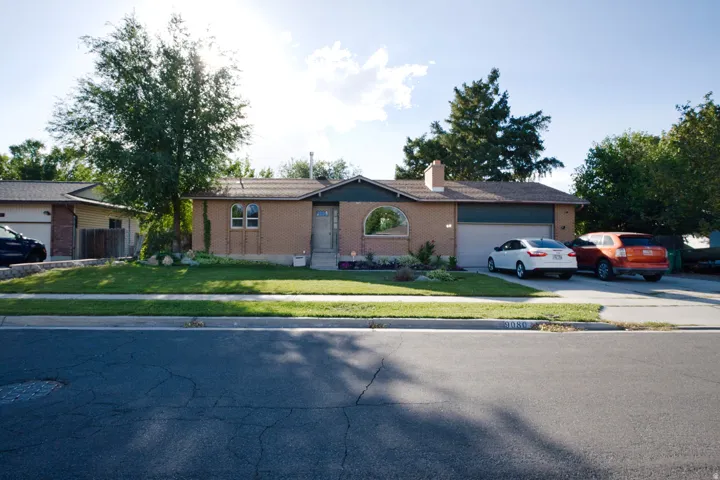 Brick exterior with arched windows, attached garage, and established landscaping